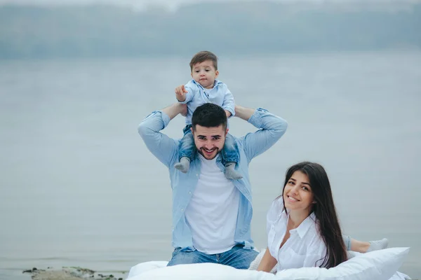 Szczęśliwa młoda rodzina relaksująca się razem nad jeziorem — Zdjęcie stockowe