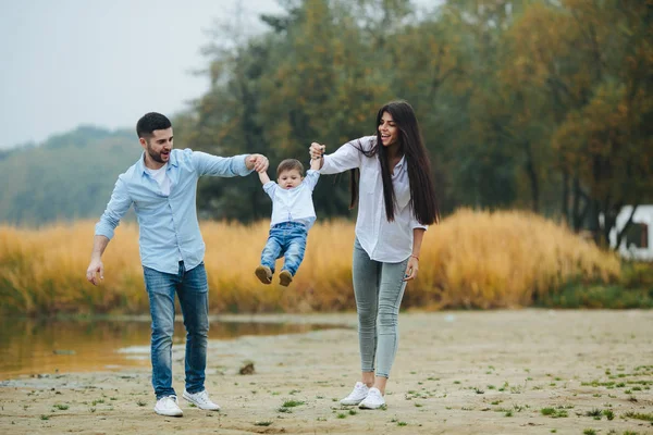 Ung familj promenader på stranden — Stockfoto