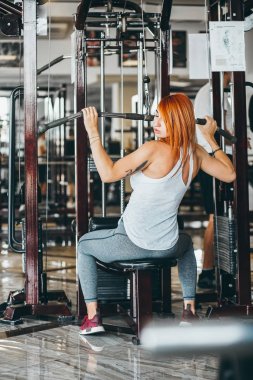 Spor salonunda sırtını ve omzunu çalıştıran bir kadın.