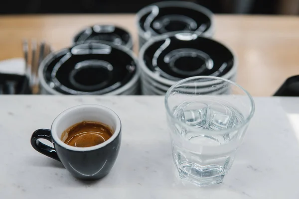 Šálek s kávou u sklenice vody — Stock fotografie