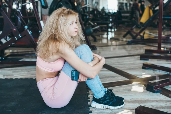 Chica se sienta en el suelo en el gimnasio —  Fotos de Stock