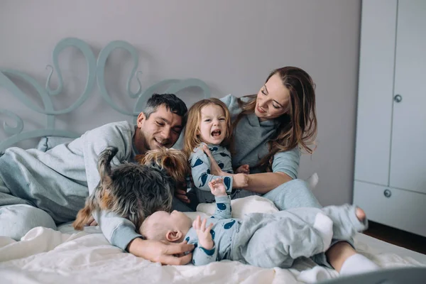 Madre, padre, figlia e bambino sul letto — Foto Stock