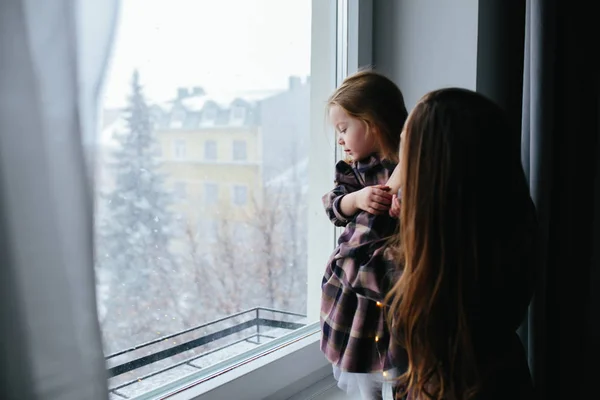 Moeder met klein meisje kijken door het raam — Stockfoto