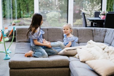 büyük kanepede birlikte oynayan iki kız kardeş