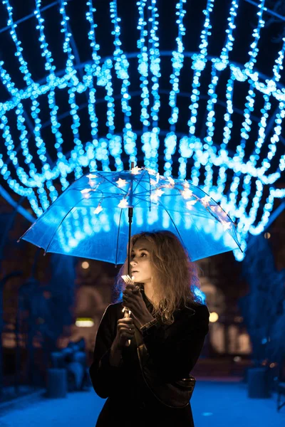 Молода жінка стоїть на освітленій алеї — стокове фото