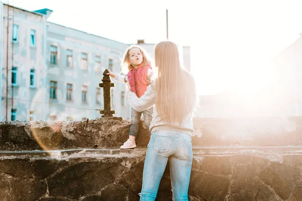 Máma a dcera sedí spolu na plotě. — Stock fotografie