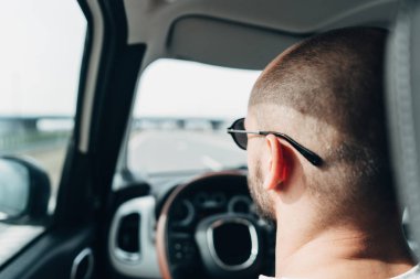 Arabadaki adam yolda gidiyor.