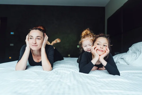 Anne ve iki kızı yatakta eğleniyor. — Stok fotoğraf