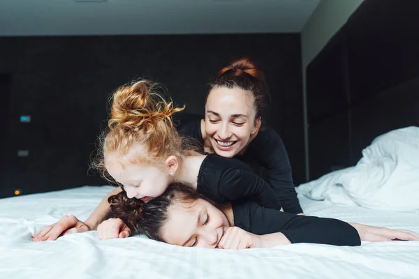 Mom and two daughters have fun on the bed — Stock Photo, Image