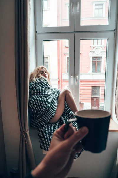 Girl sitting on a window in a blanket — Stock Photo, Image