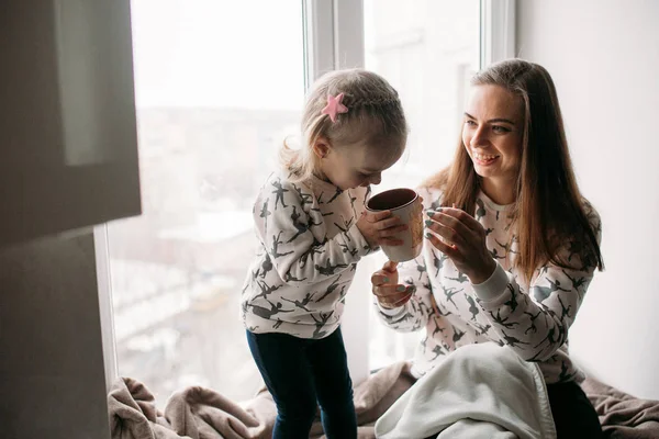 Maman et fille boivent quelque chose avec une tasse — Photo