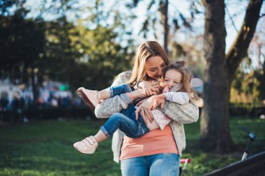 Anne kucağında küçük bir kız çocuğu tutuyor.