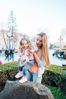 Anne kucağında küçük bir kız çocuğu tutuyor.