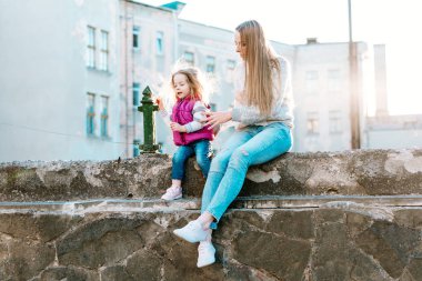 Anne ve kızı çitte birlikte oturuyorlar.