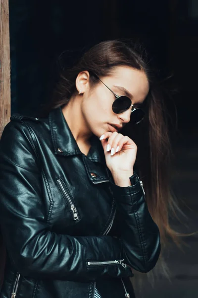 Hermosa chica en una chaqueta negra y gafas de sol — Foto de Stock