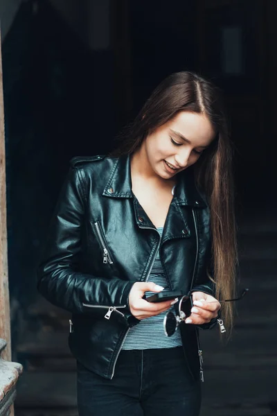 Vakker jente i svart jakke med smarttelefon – stockfoto