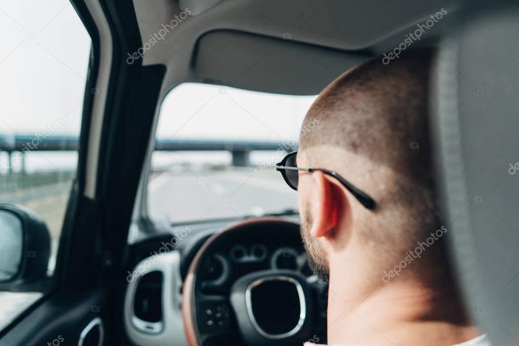 The man in the car traveling on the road