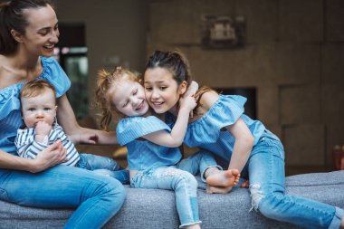 Anne, iki kız ve küçük bir oğlan kanepede.