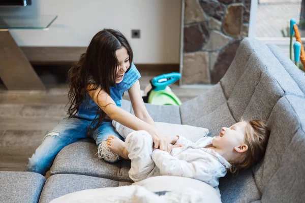 Zwei Schwestern spielen zusammen auf der großen Couch — Stockfoto