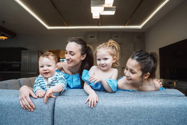 Anne, iki kız ve küçük bir oğlan kanepede.