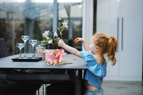 Little girl puts flowers on table — Stock Photo, Image