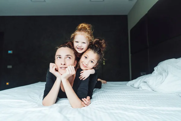 Mom and two daughters have fun on the bed — Stock Photo, Image