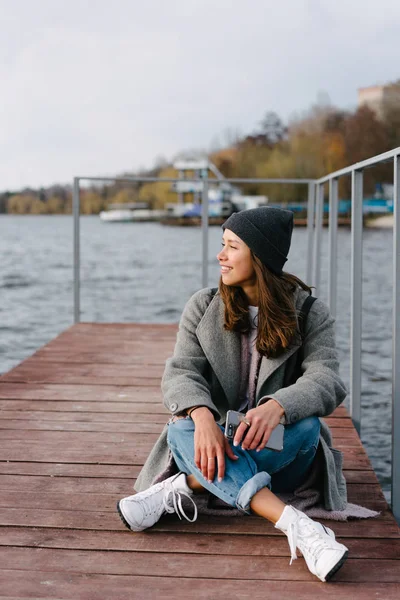 Mladá hezká dívka na dřevěné lavici na starém molu — Stock fotografie