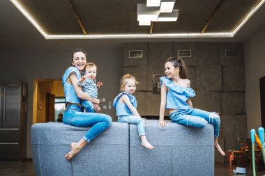 Anne, iki kız ve küçük bir oğlan kanepede.