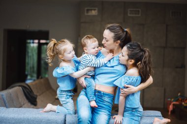 Anne, iki kız ve küçük bir oğlan kanepede.