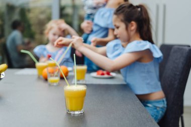 İki kız kardeş mutfakta meyve suyu içiyor.