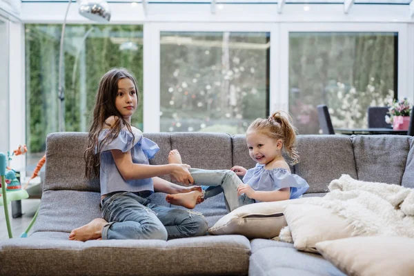 Zwei Schwestern spielen zusammen auf der großen Couch — Stockfoto