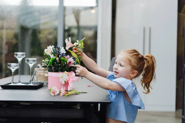 Little girl puts flowers on table — Stock Photo, Image