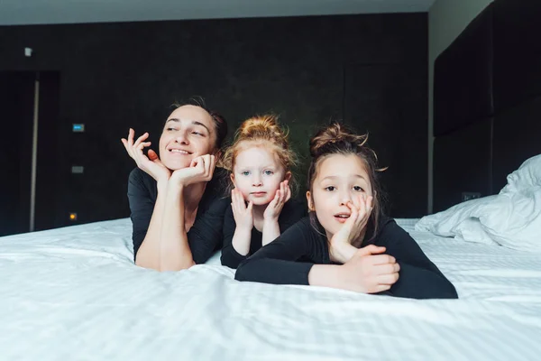 Mom and two daughters have fun on the bed — Stock Photo, Image