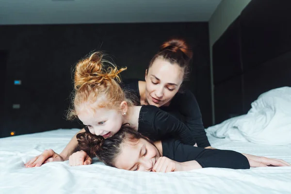 Mamá y dos hijas se divierten en la cama —  Fotos de Stock