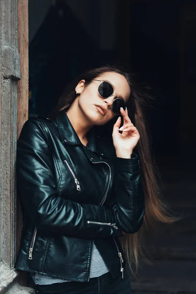 Menina bonita em uma jaqueta preta e óculos de sol — Fotografia de Stock