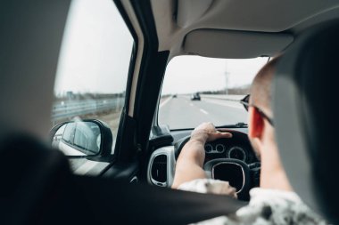 Arabadaki adam yolda gidiyor.