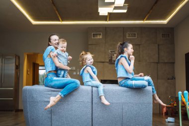 Anne, iki kız ve küçük bir oğlan kanepede.