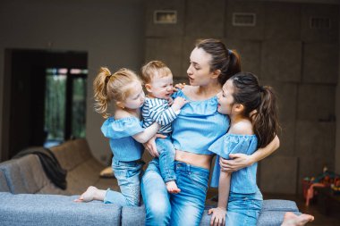 Anne, iki kız ve küçük bir oğlan kanepede.