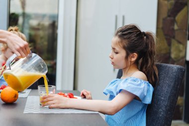 İki kız kardeş mutfakta meyve suyu içiyor.