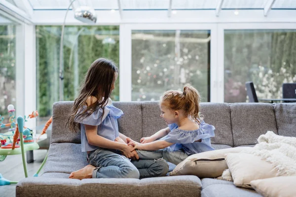 Büyük kanepede birlikte oynayan iki kız kardeş — Stok fotoğraf