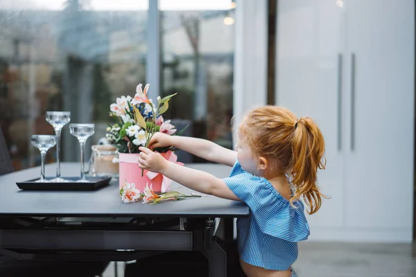 Kleines Mädchen legt Blumen auf den Tisch — Stockfoto