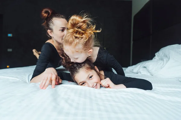 Mom and two daughters have fun on the bed — Stock Photo, Image