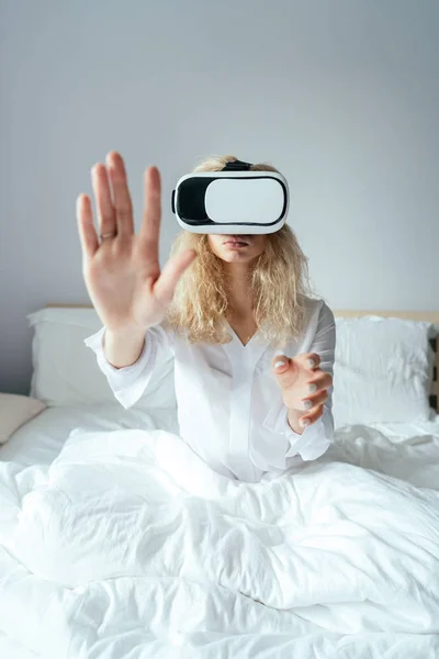 Dívka sedící na posteli s VR sluchátky — Stock fotografie