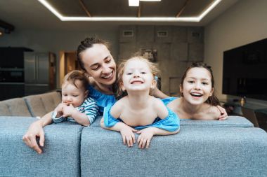 Anne, iki kız ve küçük bir oğlan kanepede.