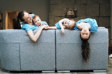 Anne, iki kız ve küçük bir oğlan kanepede.