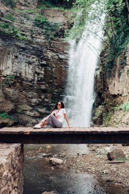 Kız köprüde oturuyor.