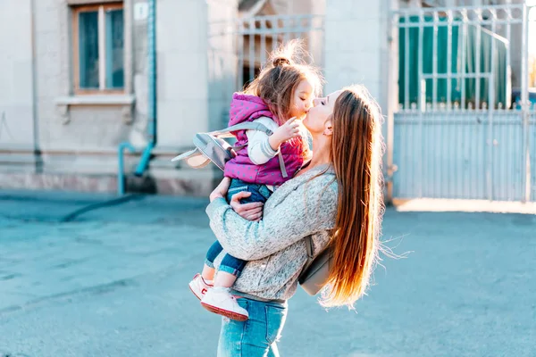 Anne kucağında küçük bir kız çocuğu tutuyor.