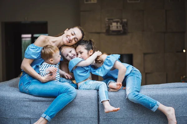 Mami, dvě dcery a malý syn na gauči. — Stock fotografie