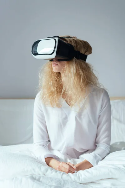 Dívka sedící na posteli s VR sluchátky — Stock fotografie
