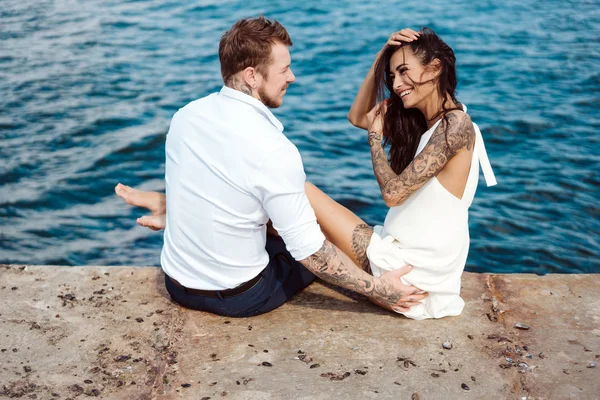 Genç çift deniz kıyısındaki iskelede oturuyor.